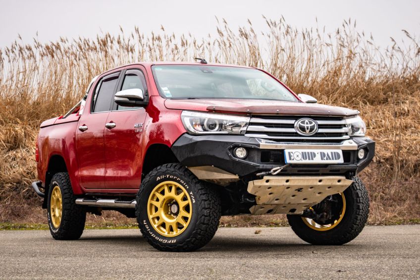 Toyota Hilux Revo rouge équipé de nouveaux pare-chocs, de jantes dorées Evo corse et d'un treuil par Equip'Raid equipement 4x4 tout-terrain